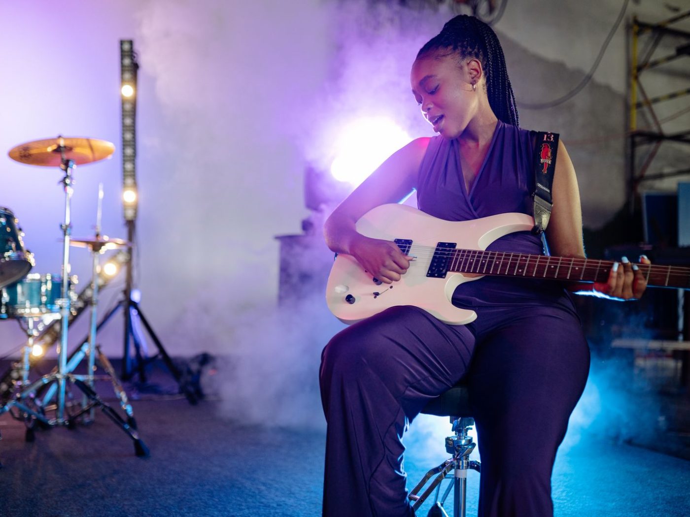 Singer playing guitar on stage under coloured lights